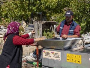 Üzüm sıkma makinesi çalışıyor, üretici keyfine bakıyor